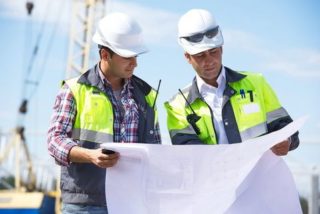 Civil engineers at construction site is inspecting ongoing works according to design drawings.